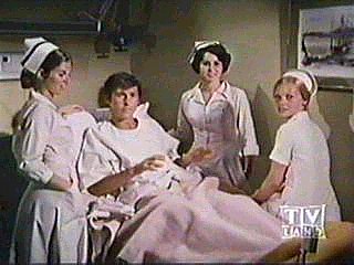 Image of jsurroundedbynursesinbed.jpg